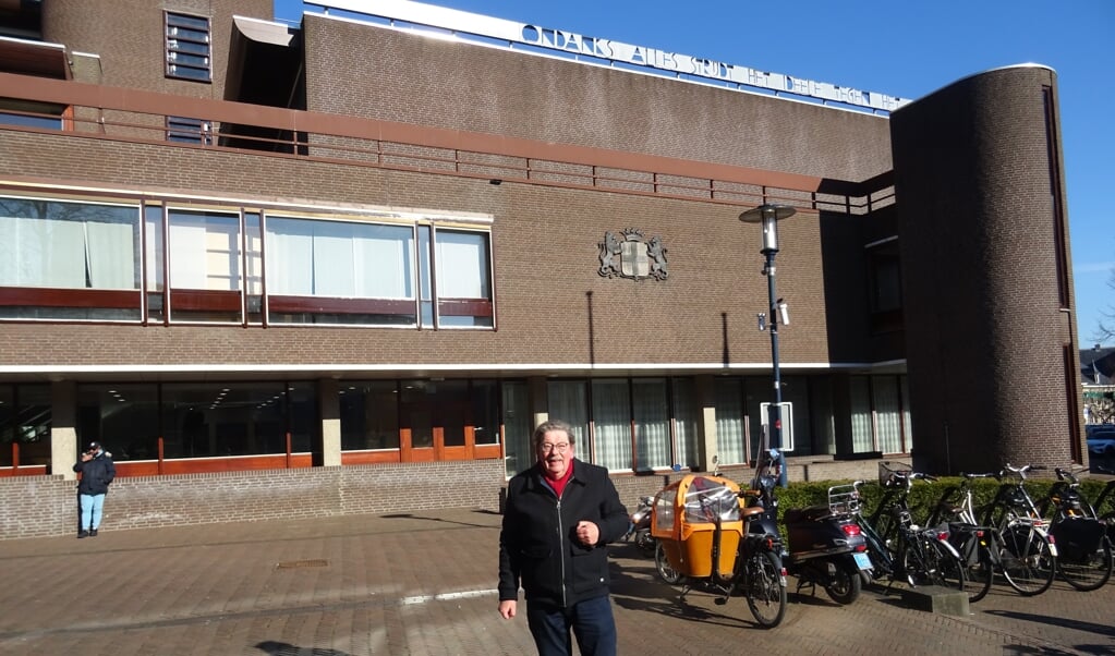 Jacques Koekkoek bij het stadhuis, boven het gebouw hangt een van de vier werken. ,,De letters zijn slecht verlicht."