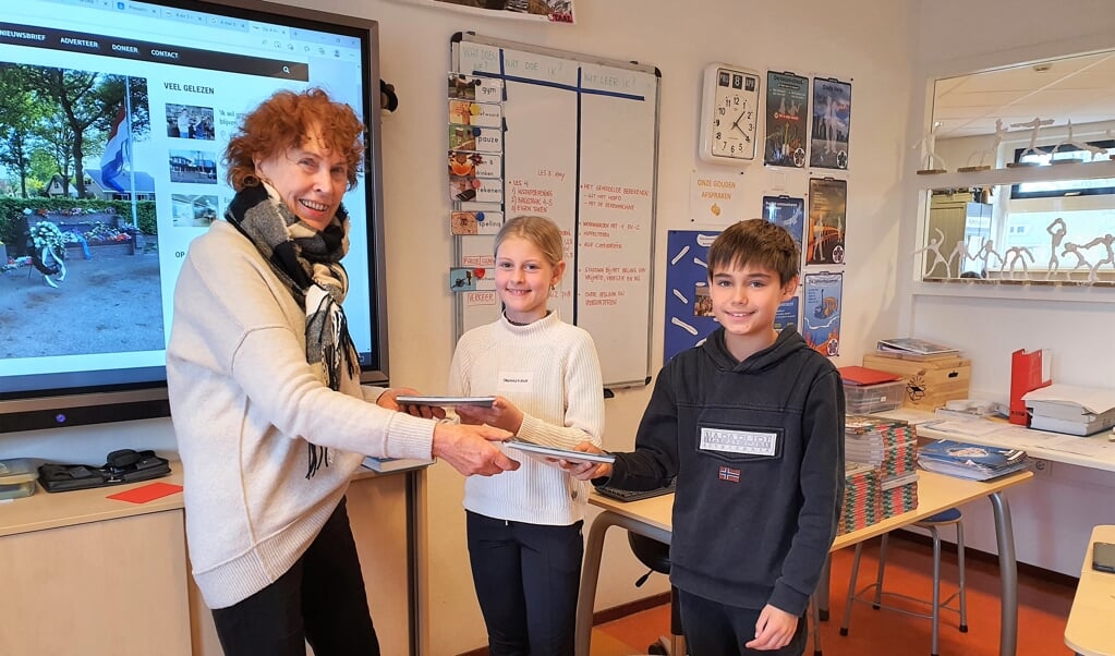 Anneke Nagtegaal overhandigt het Denkboek aan Tim en Marit, leerlingen van groep 7 van de Wilhelminaschool.