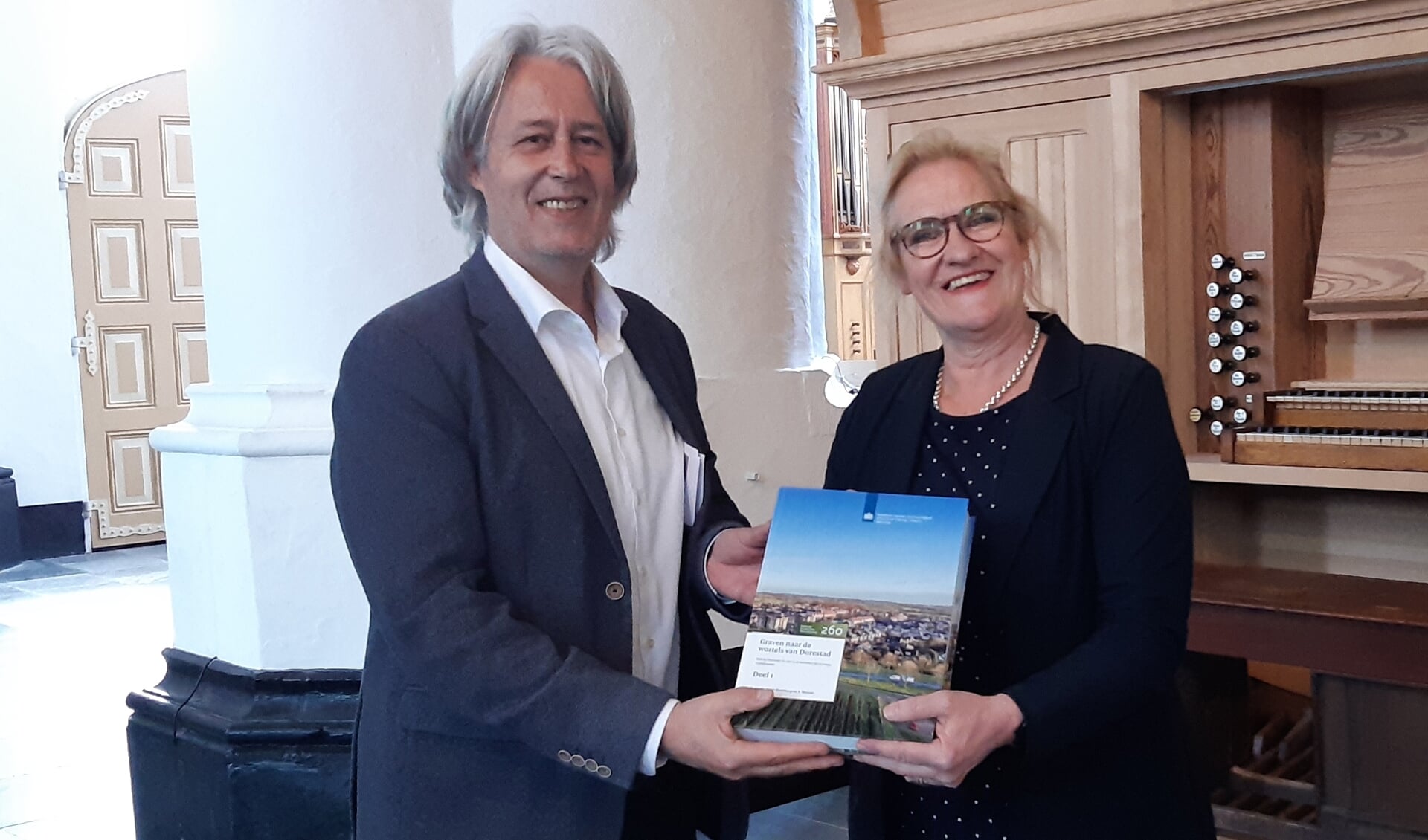 Wethouder Wil Kosterman ontvangt uit handen van archeloog Jan van Doesburg het boek over opgravingen in De Geer II