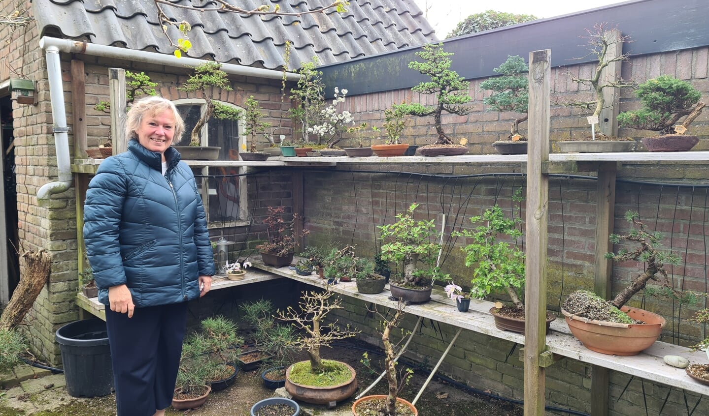 Anita van der Wal in haar achtertuin bij een deel van haar 'bomen in pot'.