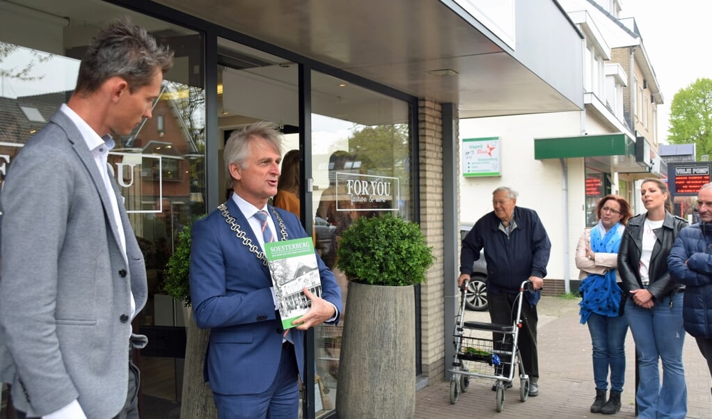 Burgemeester Rob Metz met het nieuwe plaatjesalbum over Soesterberg, hem aangeboden door winkelier Fernando Livestro (links).