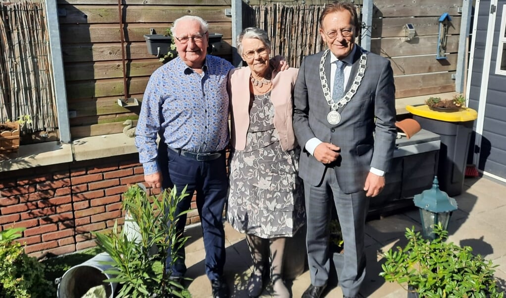 Burgemeester Janssen poseert met Piet en Ria Cinjee in hun zonnige tuin. Tuinieren is een liefhebberij van mevrouw.
