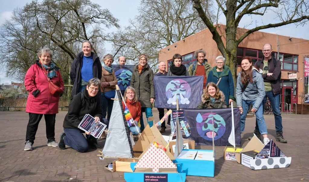 Een groep vrijwilligers met kartonnenbootjes met ideeën voor klimaatoplossingen