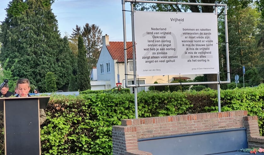Julian van den Berg leest zijn gedicht 'Vrijheid' voor. De volledige tekst staat op een groot doek bij het monument in het Bart van Elstplantsoen.