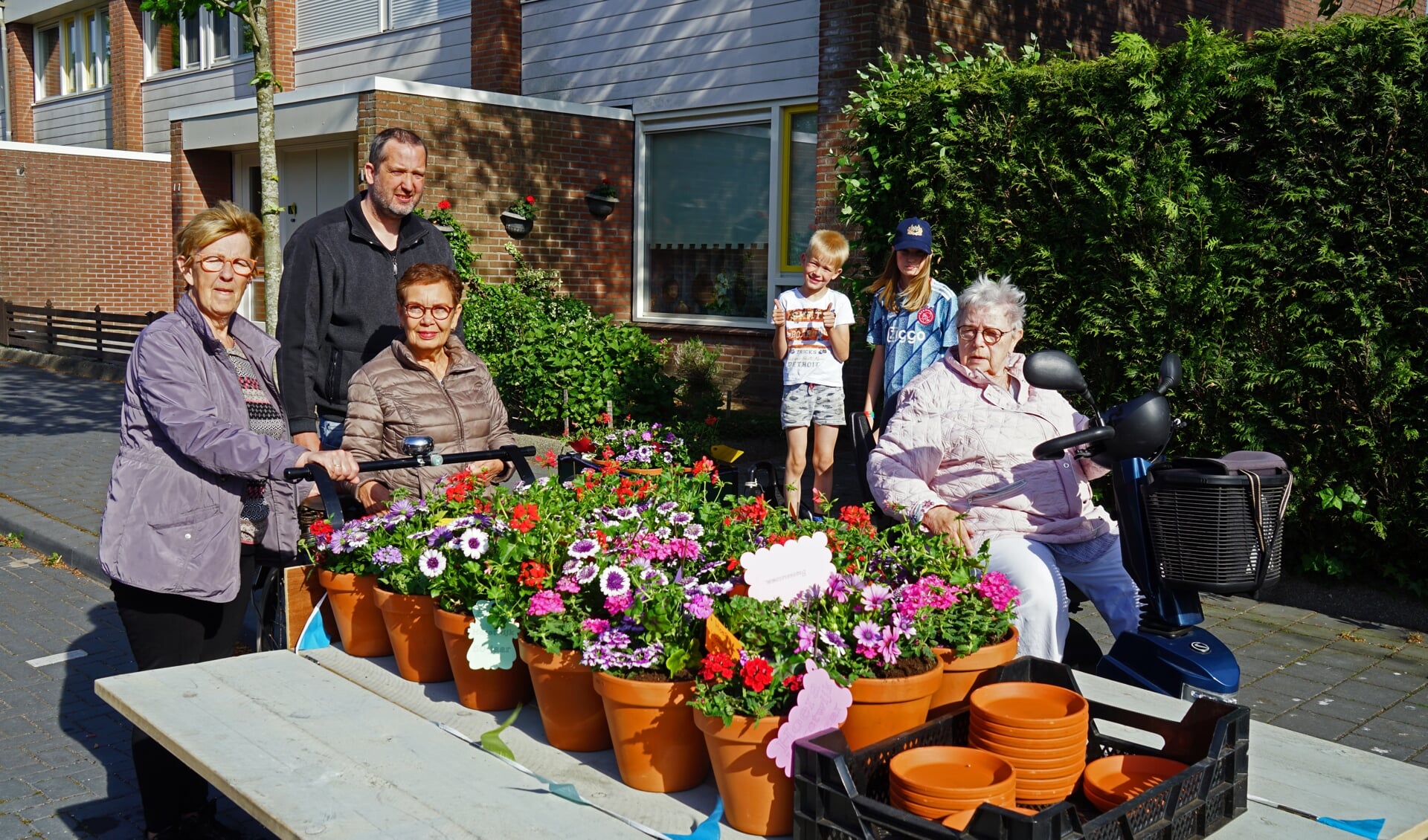 Mieke Koudijs, Rita Pfister en  Marie TImmerman met de fleurige attentie voor bewoners Horstwijk laag. Ook op de foto staat buurman Ronald en zijn kinderen Lucas en Jessica.