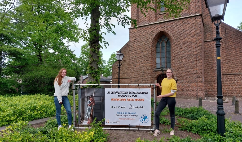 Nienke Verrips (links) en Gerlise Veenendaal van Jeugdvereniging Het Knipperlicht met de banner van de actie.