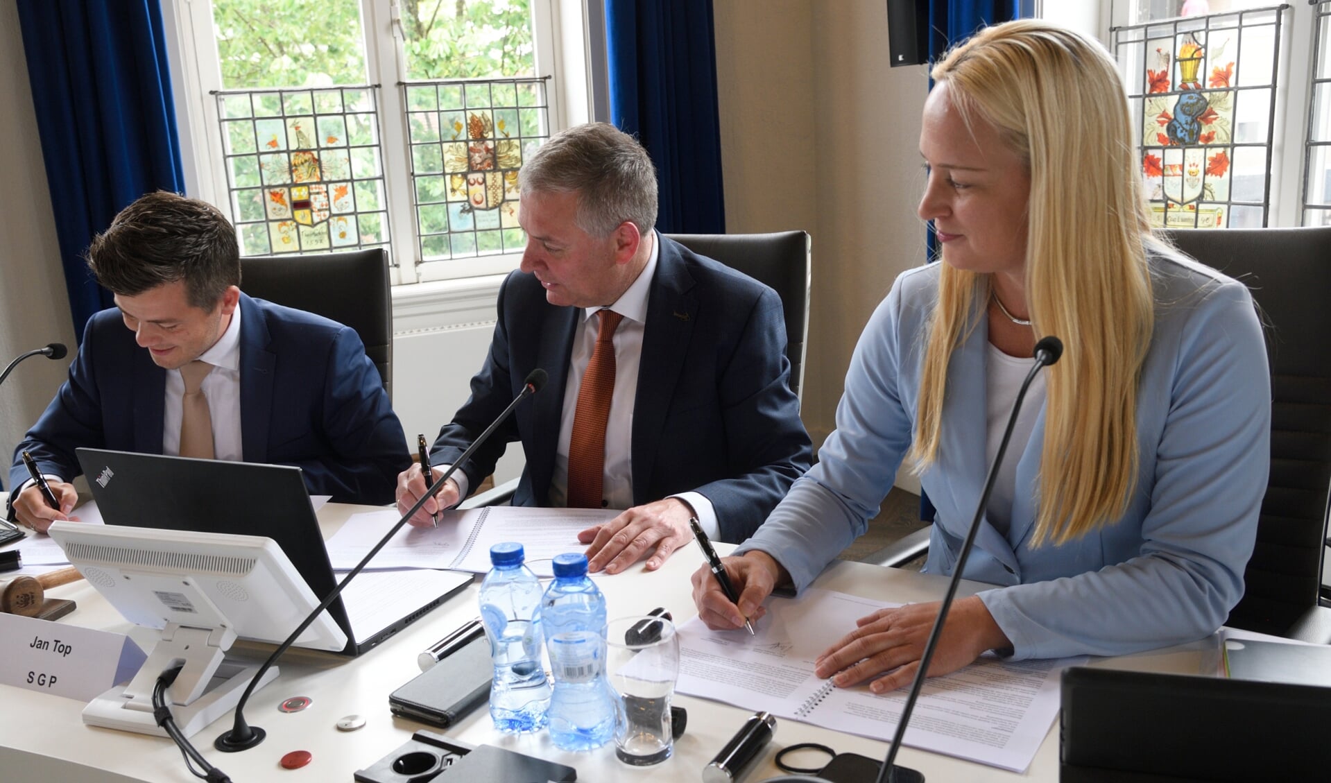 Henk Wiesenekker (links), Jan Top en Mijntje Pluimers ondertekenen het coalitieakkoord.