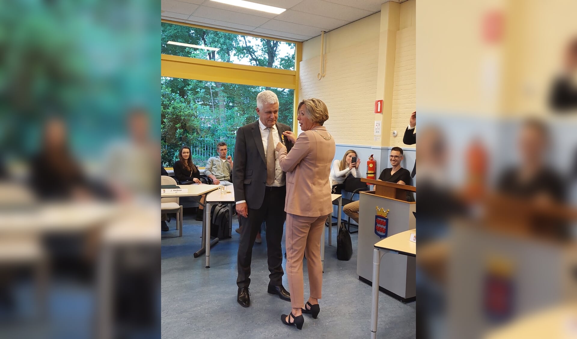 Henk van der Schoor krijgt de koninklijke onderscheiding opgespeld door burgemeester Petra Doornenbal.