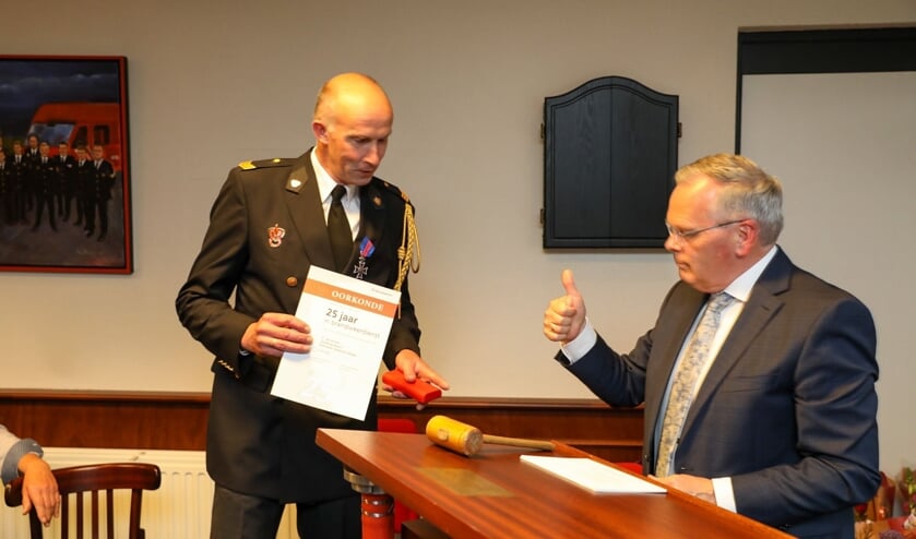Jubilaris Gerrit van de Kieft (25 jaar) krijgt behalve een oorkonde en een medaille ook een 'duimpie' van burgemeester Jan Luteijn
