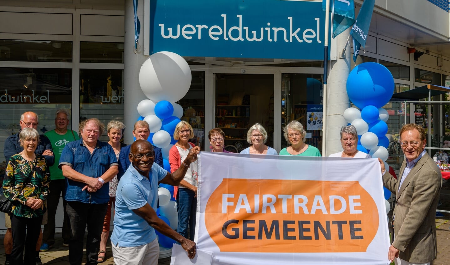 De wereld winkel in Zeist bestaat 50 jaar. Burgemeester Janssen en Cor Doelwijt van de Fair Trade Werkgroep tonen de Fair Trade vlag voor de Wereldwinkel (2021).