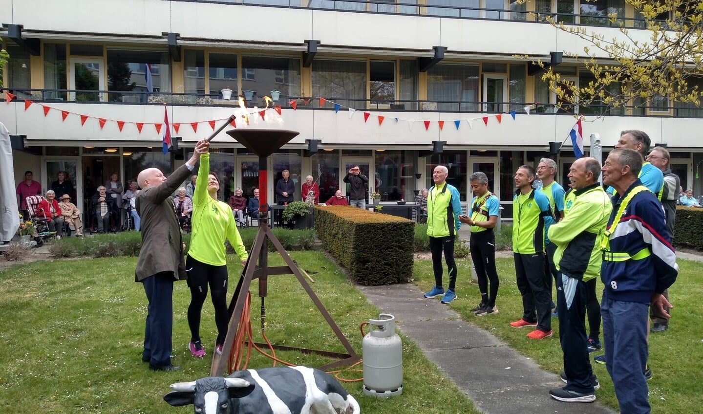 Burgemeester Van Bennekom en een van de leden van Loopgroep Bunnik ontsteken samen het bevrijdingsvuur.