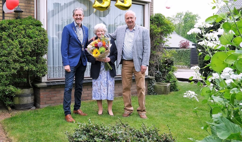 Het jubilerende echtpaar Jan en Marietje Roesink-Garsen en burgemeester Hans van der Pas in de tuin van de familie. 