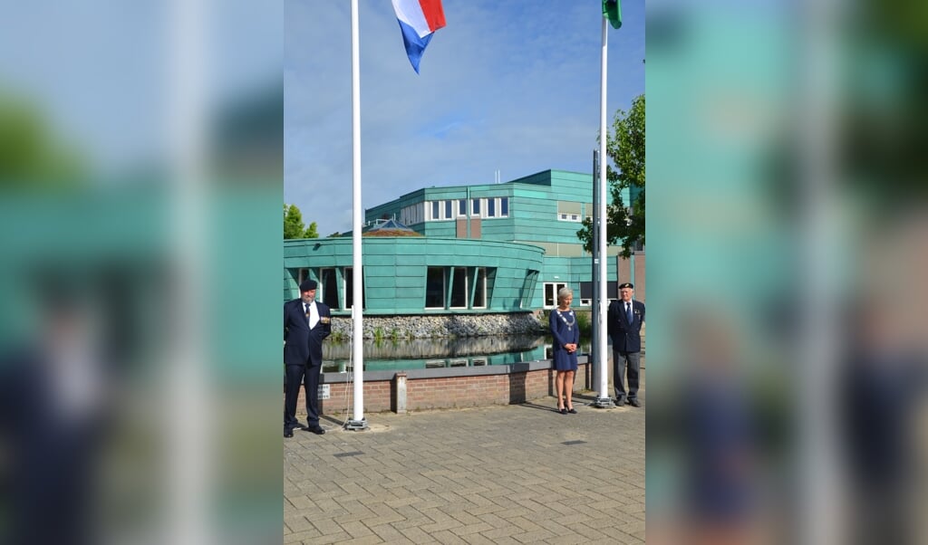 Veteranen Ton van Wette en Pieter van Eden hijsen de vlag, samen met de burgemeester