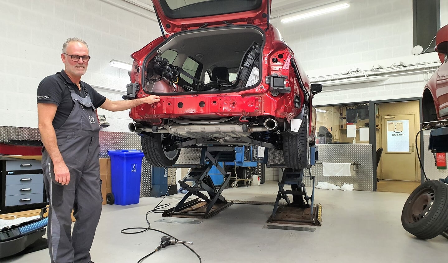 Jan Dekkers in de voor hem zo vertrouwde omgeving, de garage en sleutelend aan een Mazda. Hij werkt inmiddels al 50 jaar bij Mazda Jansen.