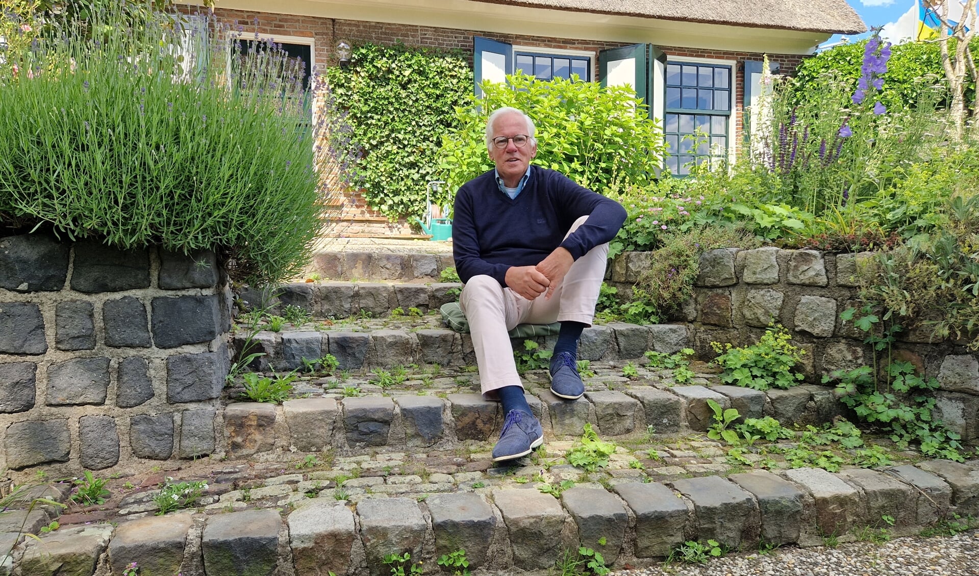 Bram in zijn tuin, waar eens het water tot aan de bovenrand van het muurtje kwam. 