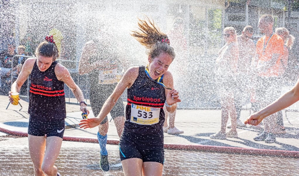 De brandweer geeft de lopers een verkoelende douche. 