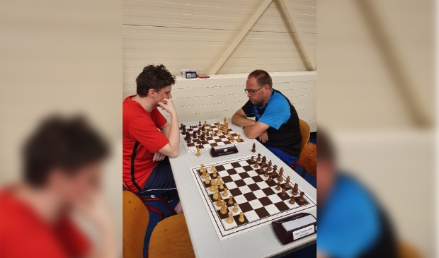 Toernooiwinnaar Bram van den Berg (rechts in het blauw) speelt in de zesde rond zijn schaakpartij tegen Sytse Koopmans.