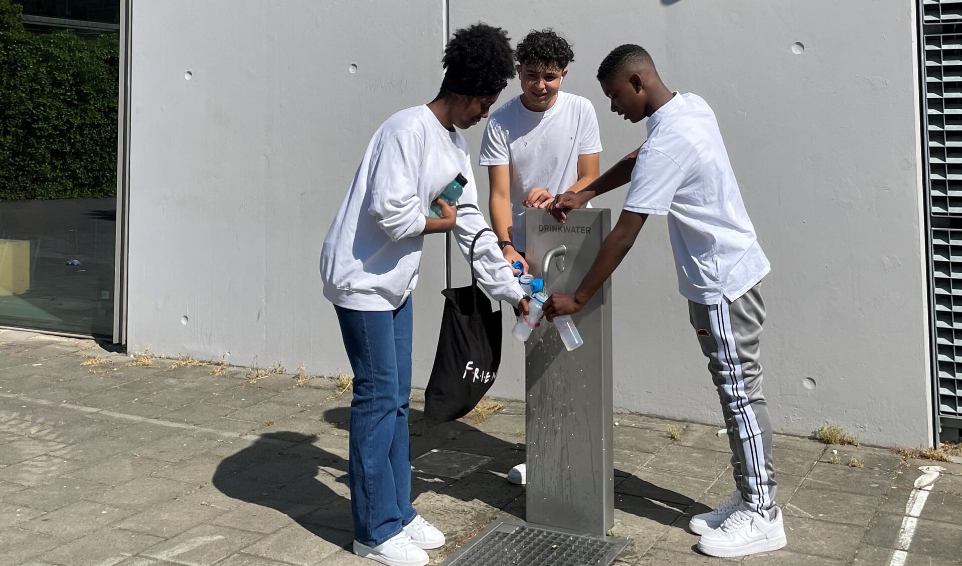 Leerlingen vullen bidon bij het nieuwe watertappunt op het schoolplein