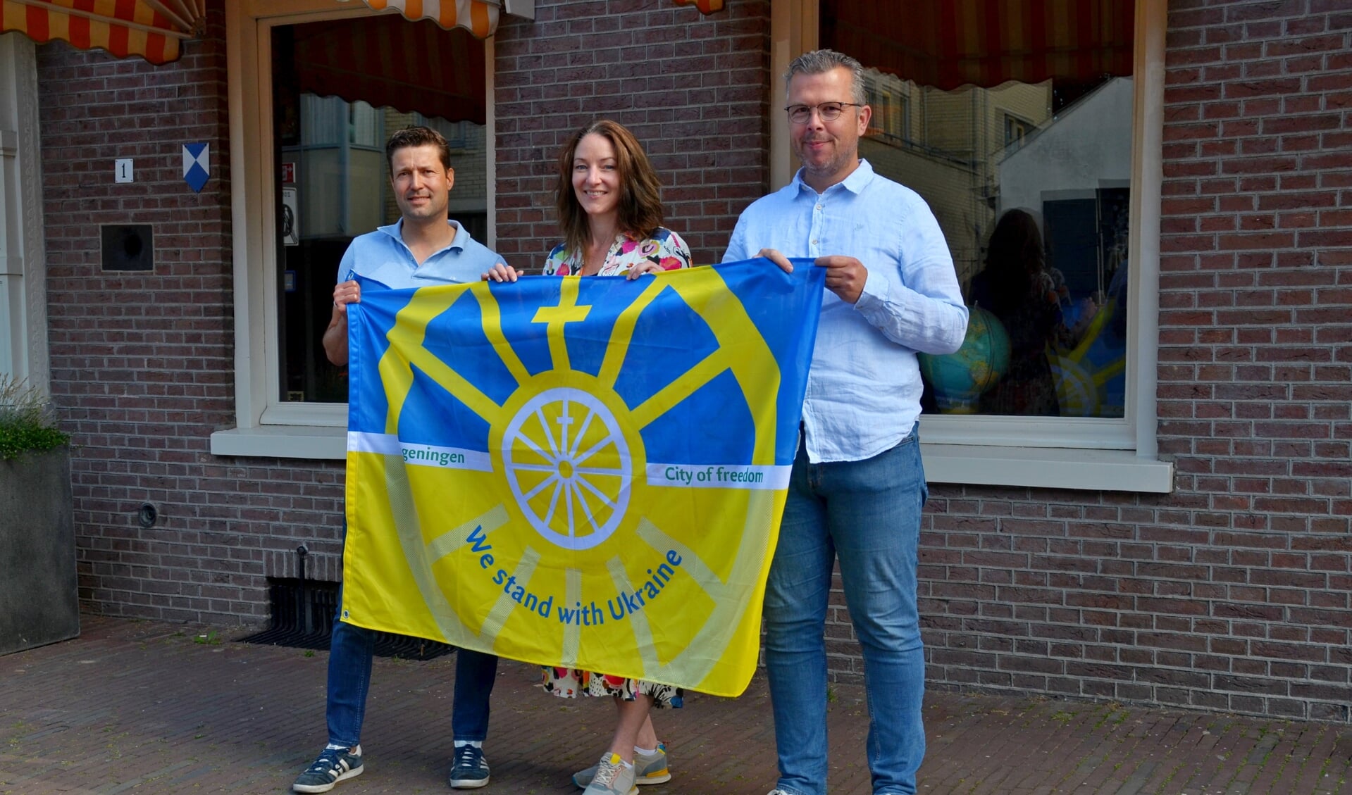 Vlnr. Ralph Koekkoek, Elke van Raamsdonk en Robert Frijlink met de speciale Wageningen/Oekraïne vlag bij hotel De Wereld