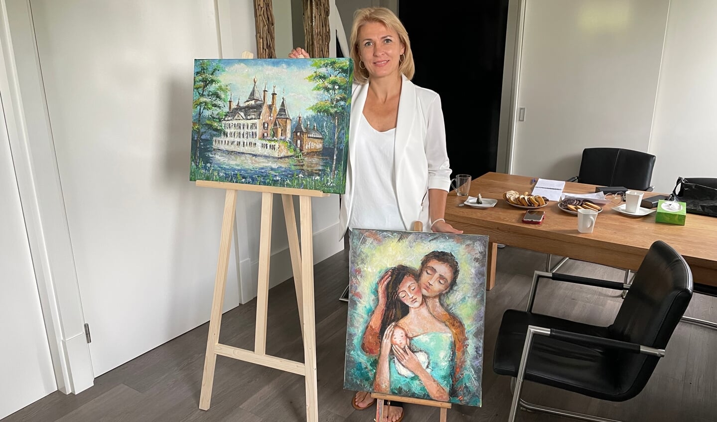Nataliia Chubko met de schilderijen die ze in Renswoude heeft gemaakt van kasteel Renswoude en een man en vrouw met kind.