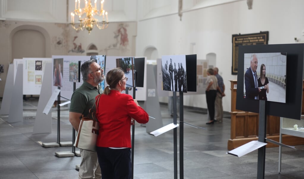 Bezoekers bekijken de foto's in de Sint-Joriskerk