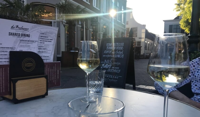 Op 15 mei zaten we op het terras van De Professor op De Hof in Amersfoort. De zon scheen fel die dag, het was warm. Daarom waren we aan de koele schaduwkant van De Hof gaan zitten, juist uit de zon. Maar de ondergaande zon kwam toch de hoek om en toen spatte het licht ons tegemoet. Het kaatste op het glas en op onze wijnglazen. Wanneer je goed in de wijnglazen kijkt, zie je dat het beeld omgekeerd in de wijn verschijnt.
Ik was jarig die dag en beschouwde het als een extra cadeautje.