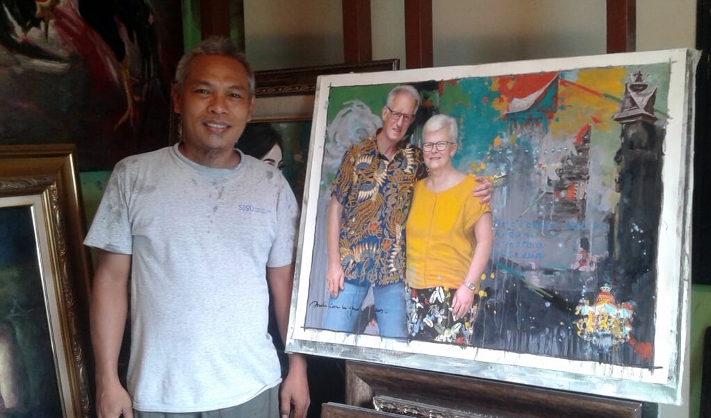 Schilder Andi Ian Surya uit Desa Kolam op Sumatra bij het door hem gemaakte schilderij van Hugo en Carla Martens uit Nijkerk. Ze hebben een bijzondere band. 