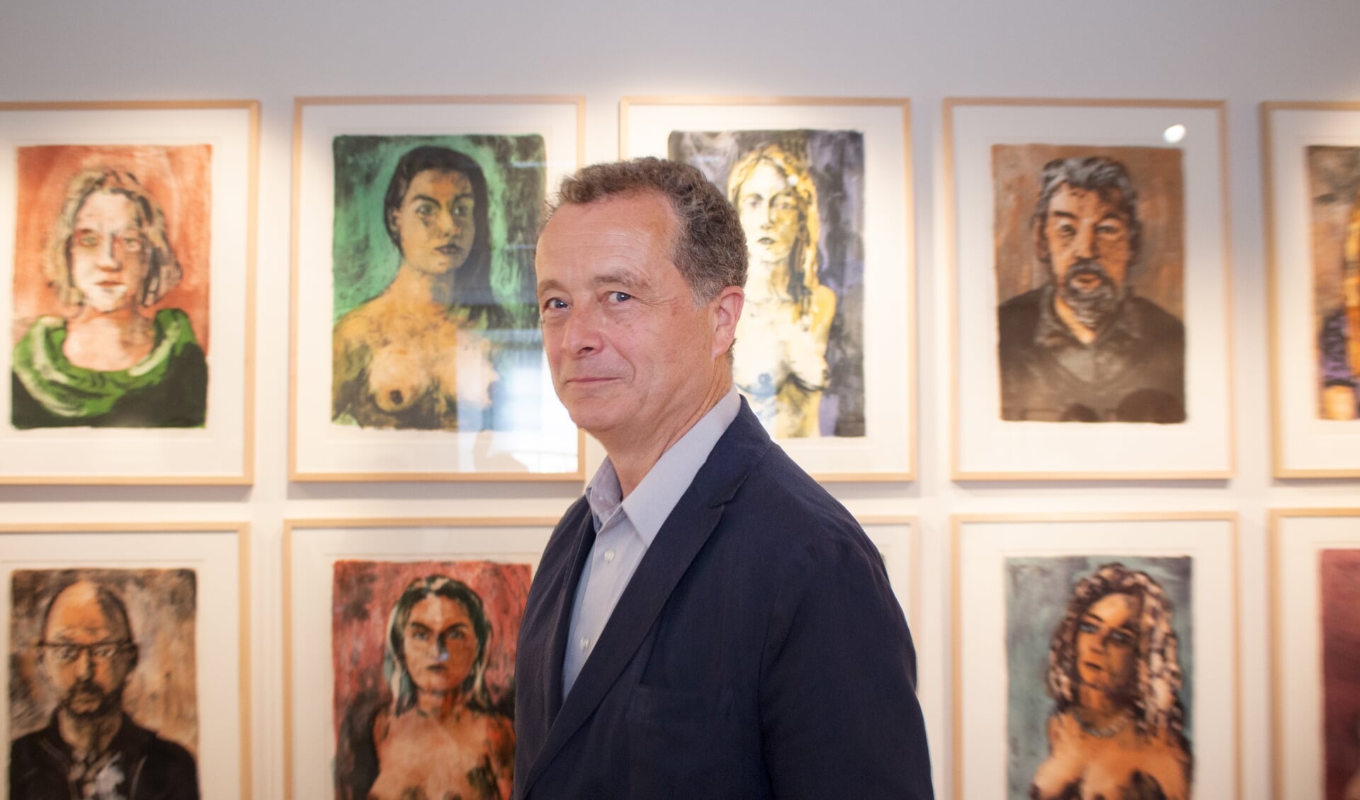 Jeroen Hermkens op de expositie. Linksonder hangt het portret van Paul Schnabel, rechtsboven dat van Maarten van Rossem.