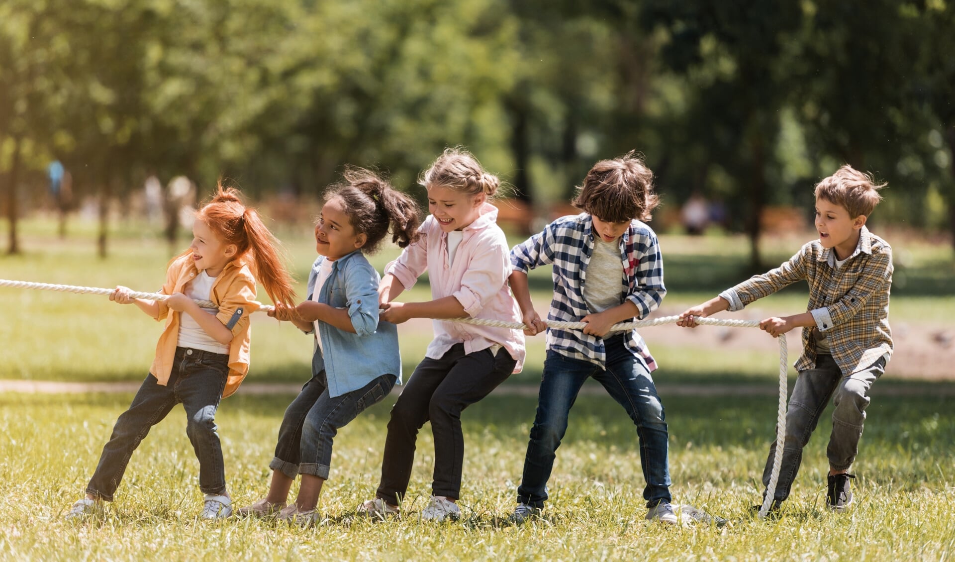 side view of adorable multiethnic kids pulling rope in park