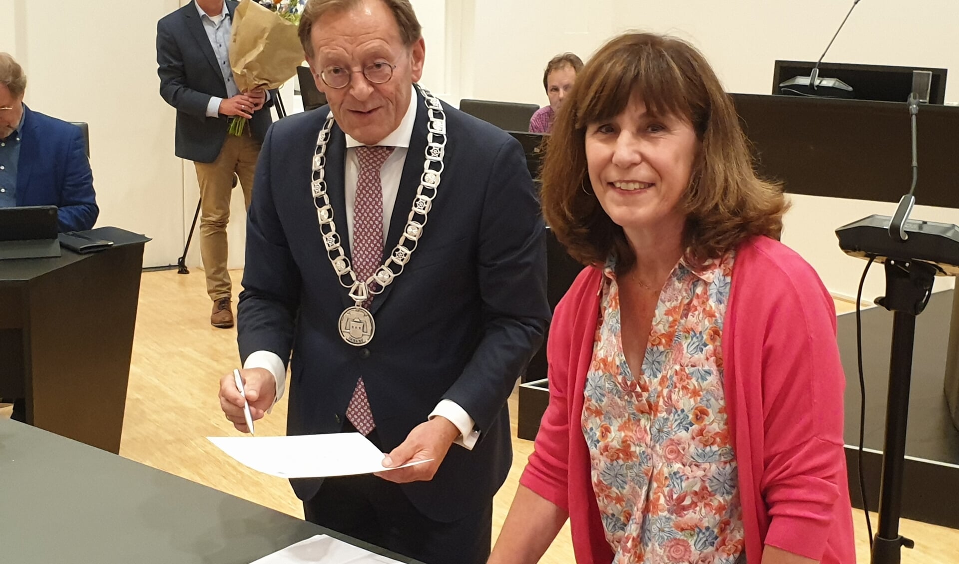 Ans Pereboom staat naast burgemeester Janssen. Ze heeft net het document getekend waarmee ze is toegetreden dot de gemeenteraad.