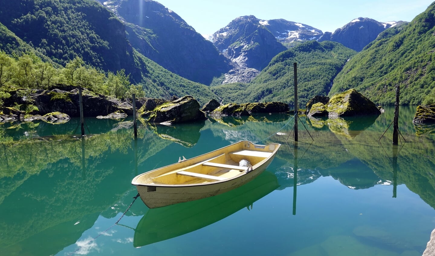 Schitterend uitzicht op de gletsjer over het spiegelende water van Bondhusvatnet in het Nationaal Park Folgefonna in Noorwegen. Het bootje ligt er volgens mij enkel voor de vele toeristen die hier komen om een foto te maken, maar dan heb je wel een mooi plaatje.