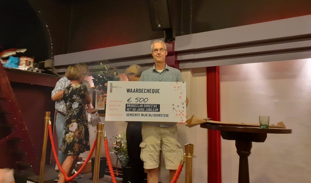 Voorzitter Mark Huisman toont de cheque die hij ontving