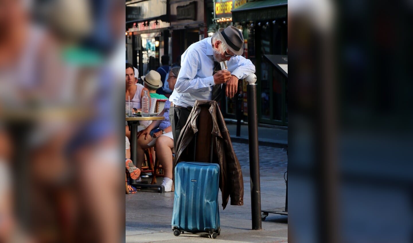 ,,In hartje Parijs, stopt een man om een sigaar aan te steken. De man lijkt iets te hebben van een zakenman, maar als je goed kijkt kan het ook net zo goed een dakloze man zijn. En waarom heeft hij de steun van die paal eigenlijk nodig? De foto is gemaakt op 11 juli.