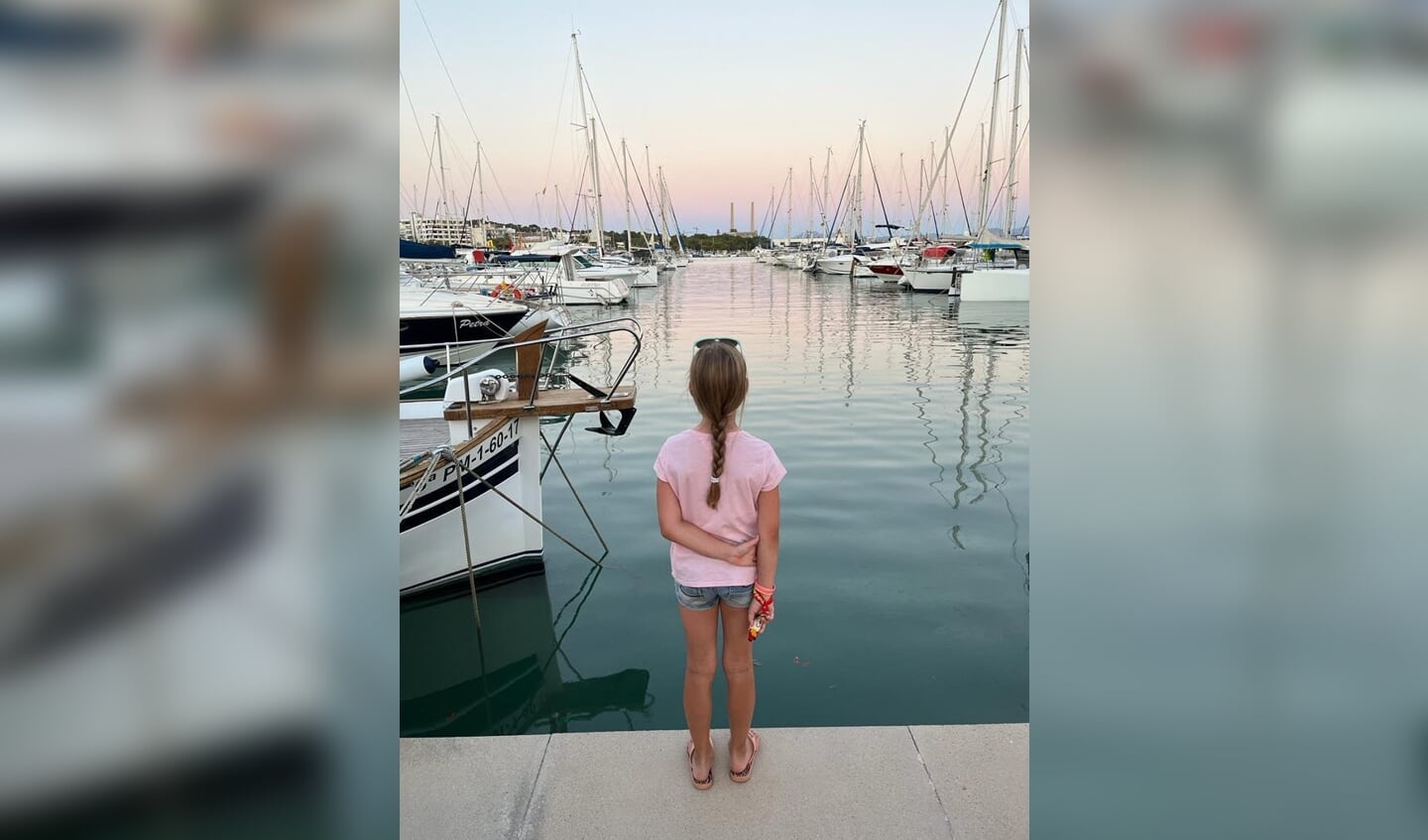 ,,Graag doen wij mee aan de zomerfotowedstrijd in de Rijnpost. Op de foto is onze dochter Britt van 9 jaar te zien. Ze kijkt in de haven van Alcudia in Mallorca over het water. Het was dit jaar zo warm in Spanje dat we vaak pas 's avonds erop uittrokken om de omgeving te verkennen, zoals hier op de foto.