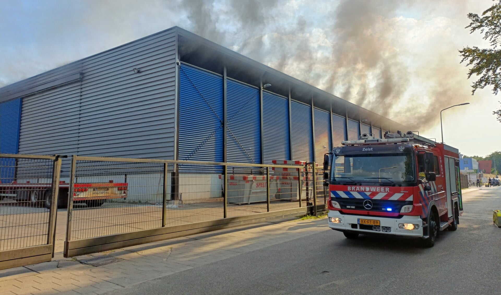 Rookwolken komen onder de rand van het dak van een afvalverwerkingsbedrijf in Den Dolder vandaan.