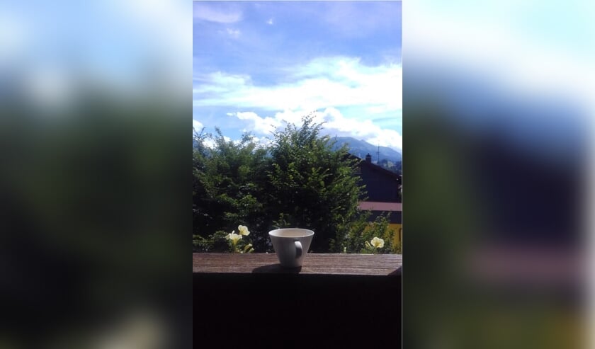 ,,Een kopje thee op het balkon van een typisch Duits hotelletje met bloembakken in de Alpen in Duitsland. Met op de achtergrond de bergen.