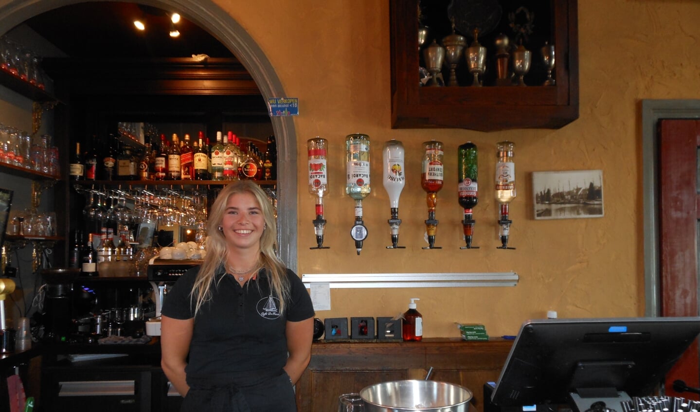 La-vie Ponstein achter de bar van café De Haven. Aan de wand achter haar één van de prijzenkasten van de voetbalclub.