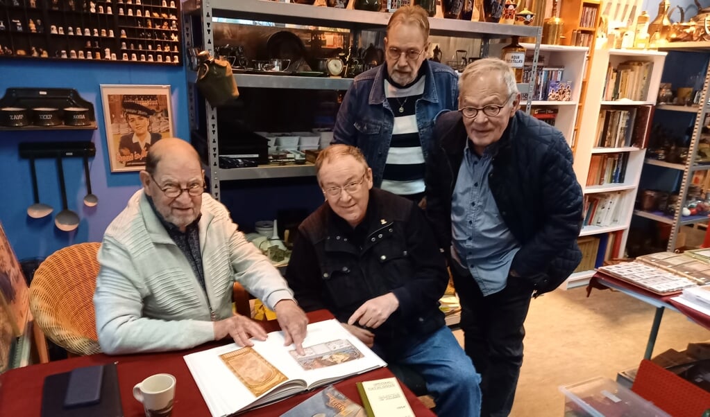 Bij handelaar in allerlei verzamelwaardige items Willem van Ruiswijk (staande links) is het altijd gezellig. Paul Hageman (l) wijst zijn vrienden Frits Kleinhans en Bert Huibens (r) op een illustratie.