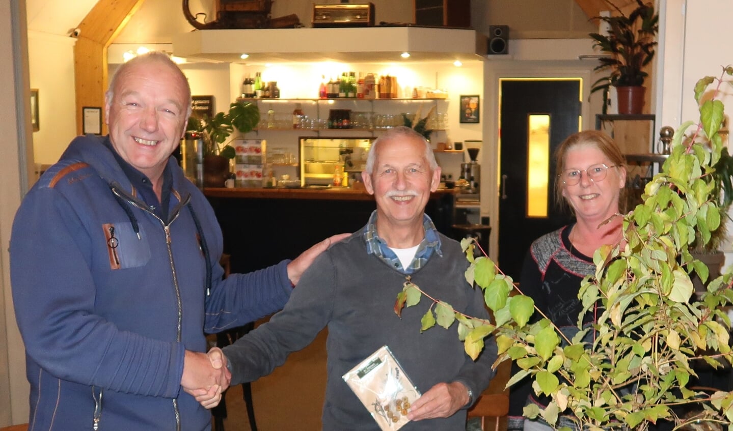 Voorzitter Ronald Floor (midden) kreeg bij zijn afscheid uit handen van secretaris Gerard van Eijden en penningmeester Monique Vollenga een rode kornoelje en een cadeaubon uitgereikt.