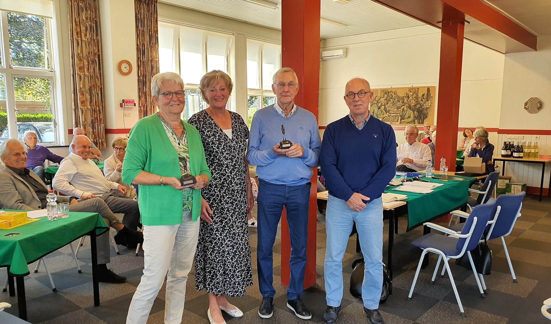 Rina (links) en Cor Weijman (tweede van rechts) ontvingen uit handen van Teun de Jong (rechts) hun 'Kei'. Ook voorzitter Martie Wagenaar-Brouwer is trots op het duo.