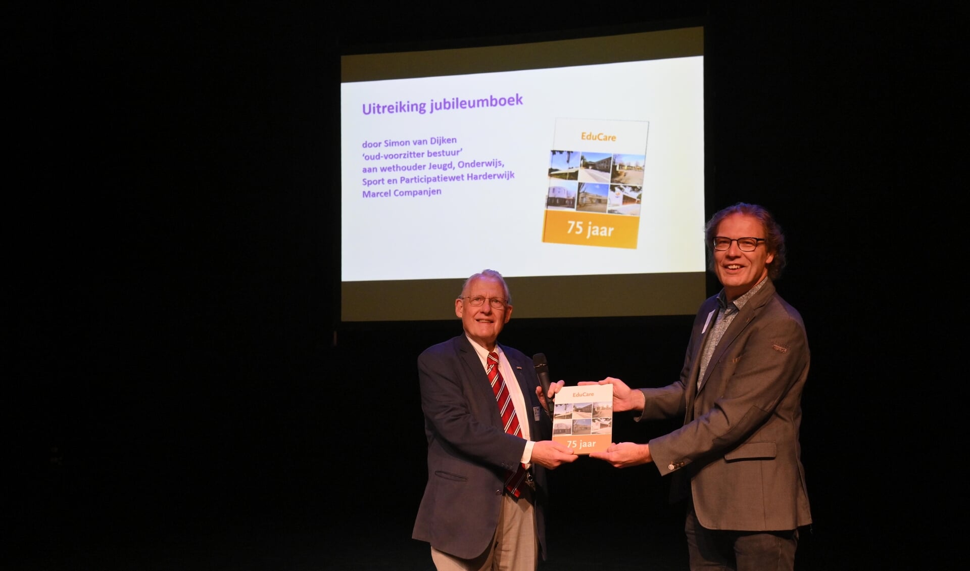 Oud-bestuurder Simon van Dijken reikt het jubileumboek uit aan wethouder Marcel Companjen. (foto: Joël Vingerling)