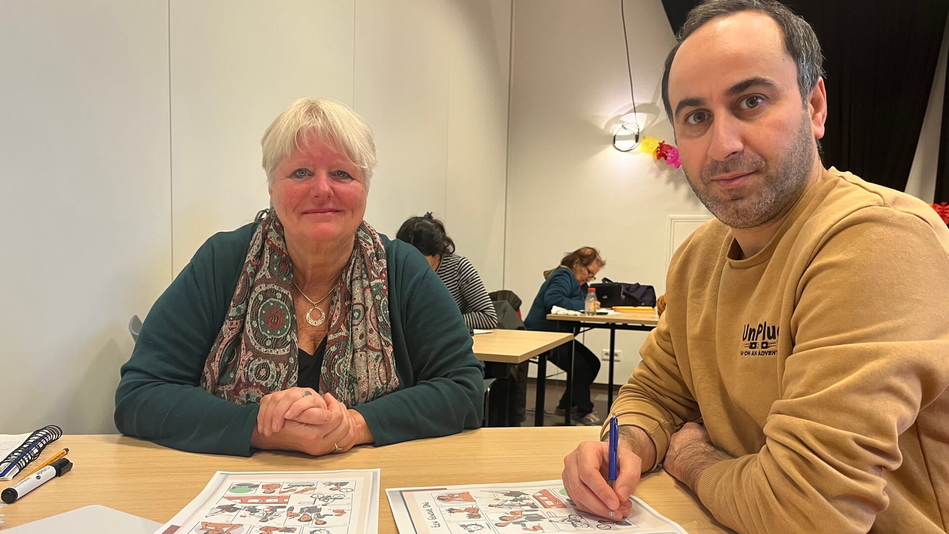 Het Taalcafé van Harderwijk helpt al vijf jaar mensen met de Nederlandse taal. Foto: taalvrijwilliger Marja helpt deelnemer Ali met de Nederlandse taal.