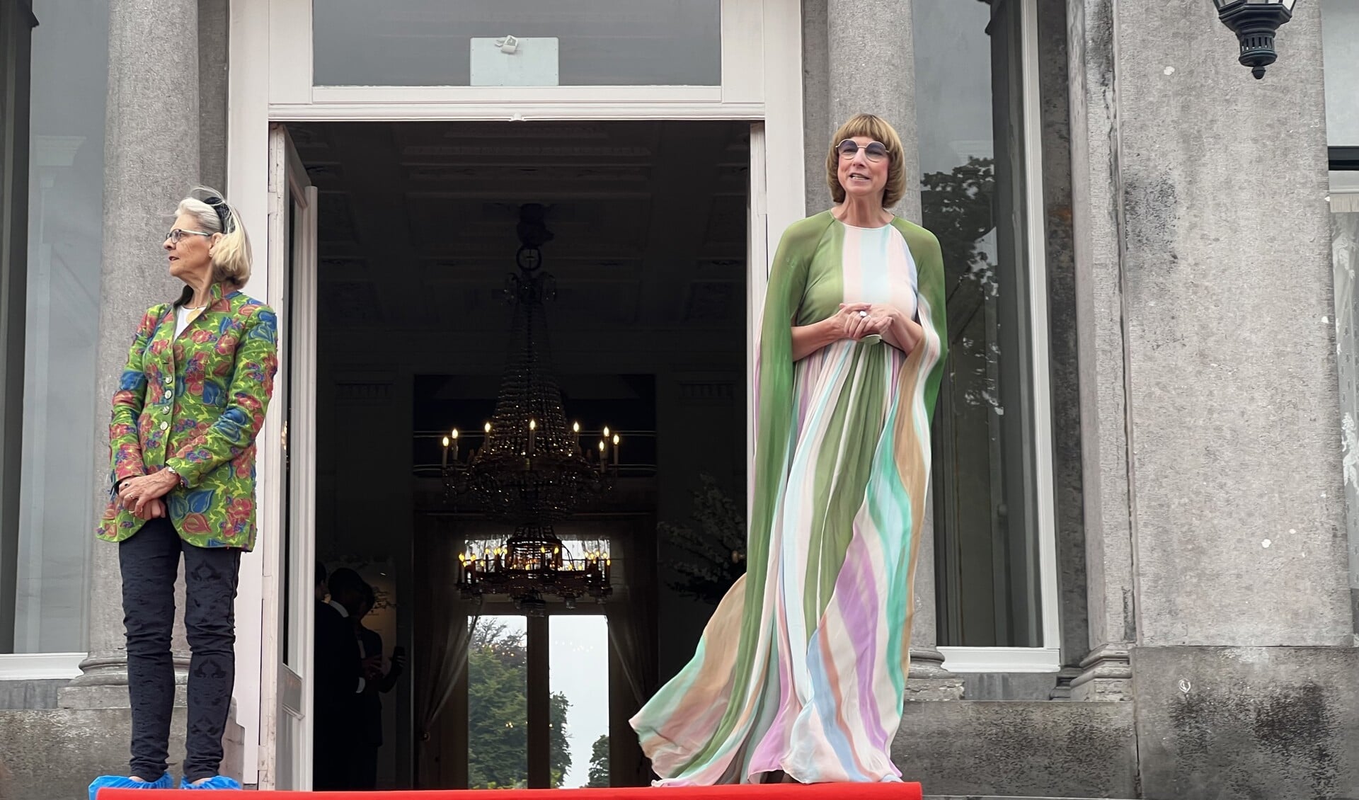 Samensteller van de expositie, Nicole Uniquole (rechts), en historica Reinildis van Ditzhuyzen op het bordes, de officiële ingang van de tentoonstelling.