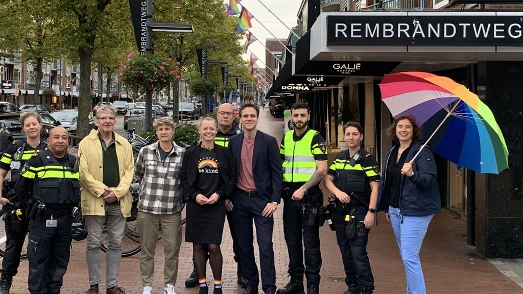 Wethouders Floor Gordon, Marijn van Ballegooijen met vertegenwoordigers van Roze in Blauw van politie, KPMG en COC op de Rembrandtweg waar de winkeliers de regenboogvlag hebben gehesen.