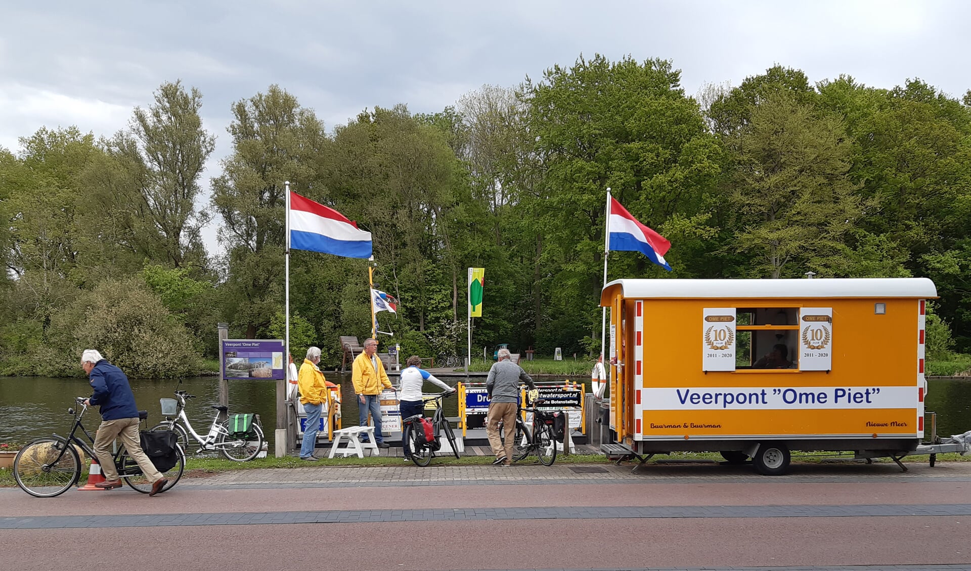 De veerpont aan de Nieuwemeerdijk. In het geel de vrijwilligers Martin (l) en Erik.