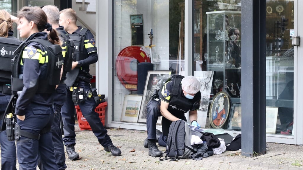 Politie onderzoekt de rugtas van de verdachte bij de kringloopwinkel bij het tankstation aan de Ouderkerkerlaan.,