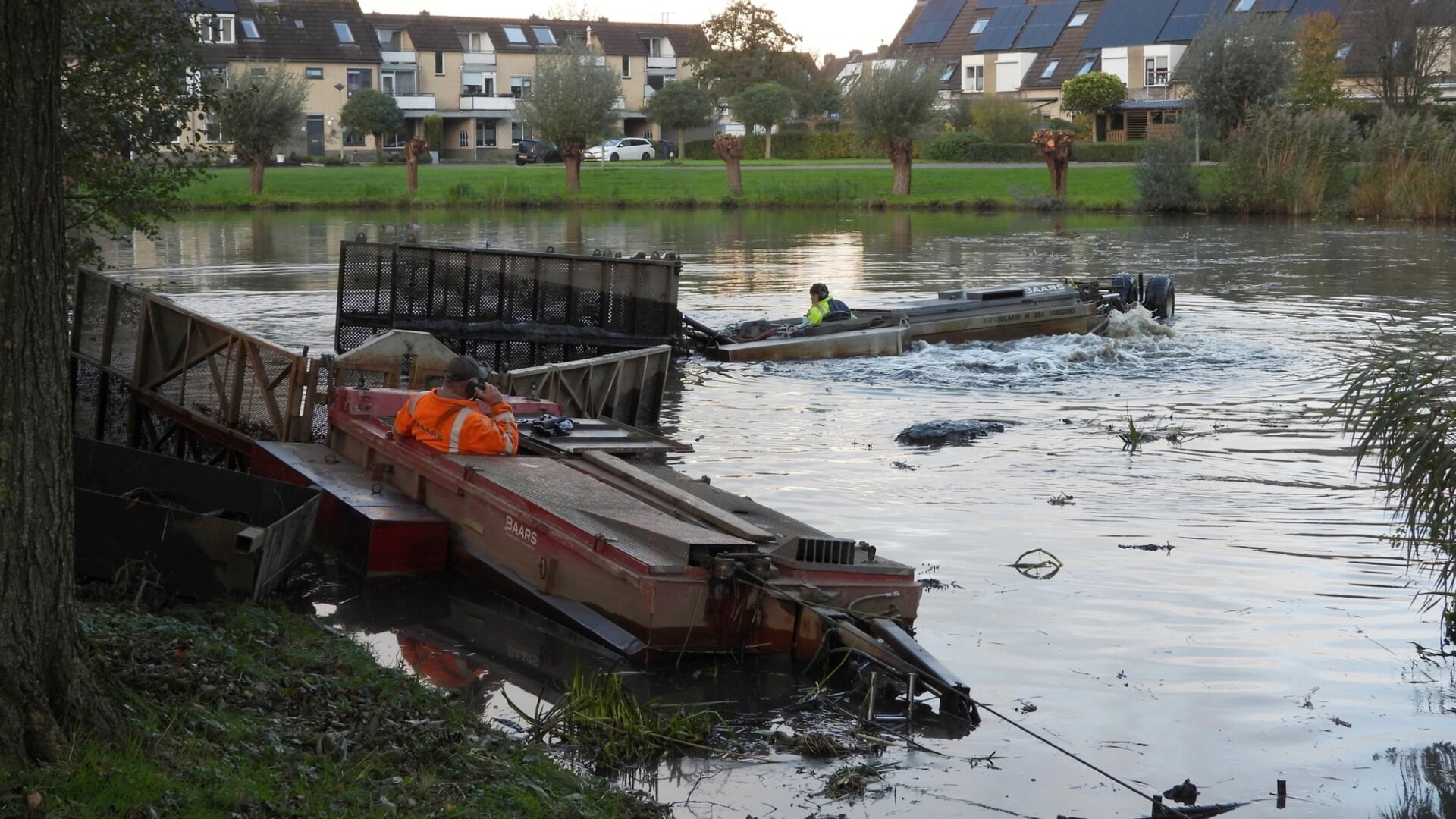 Twee schuifboten werken bodemslib naar de kant van een vijver in de Barneveldse wijk De Vaarst.