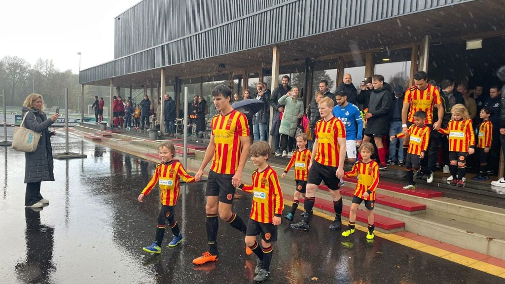 Opkomst van de spelers op sportpark Overburg in de stromende regen.