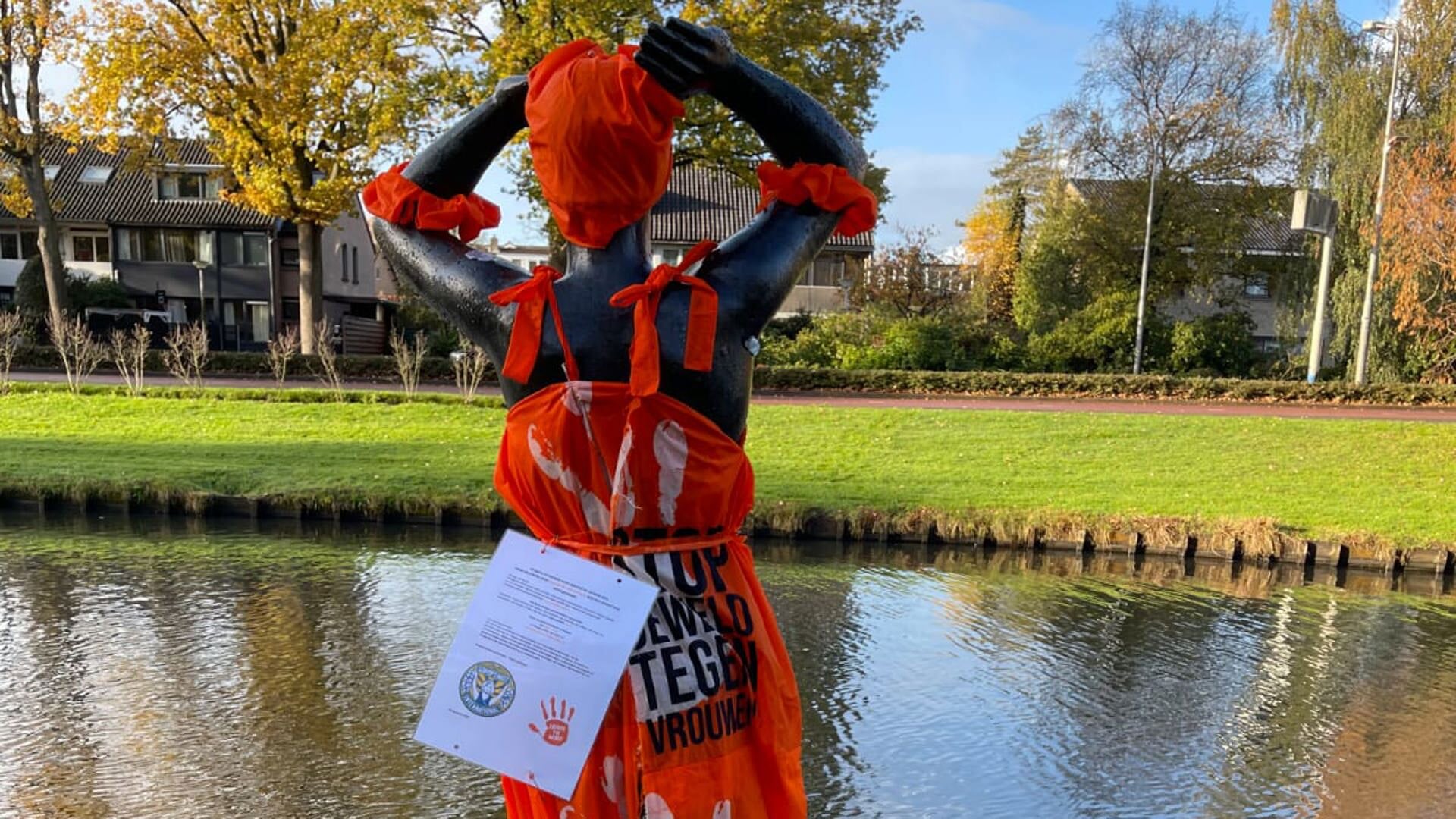 Beeld 'De Baadster' met oranje cape met oproep om geweld tegen vrouwen en meisjes te stoppen.