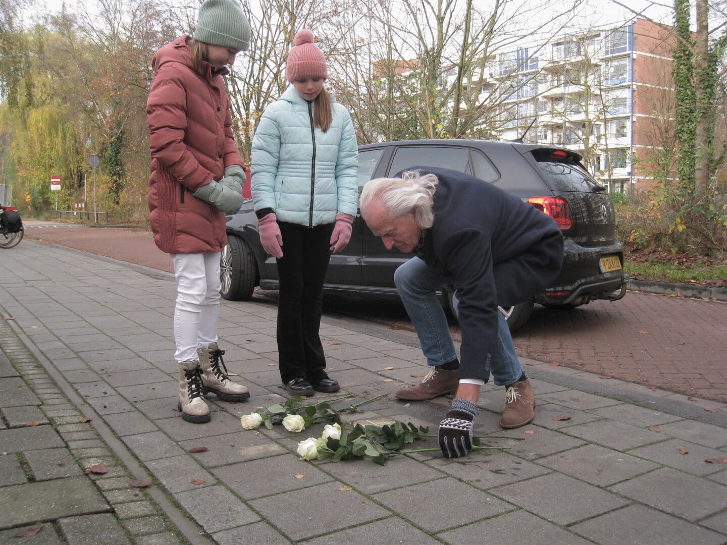 Jaap Pilon, mede-verantwoordelijk voor de komst van de gedenksteentjes in Veenendaal, bekijkt met leerlingen de steentjes.